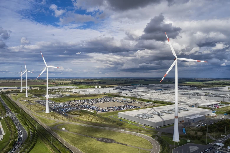 Windenergieanlagen, Industriegebäude, Straßen und Wiesen.